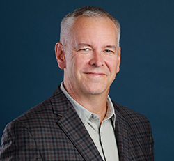 White male with short gray hair in a plaid blazer